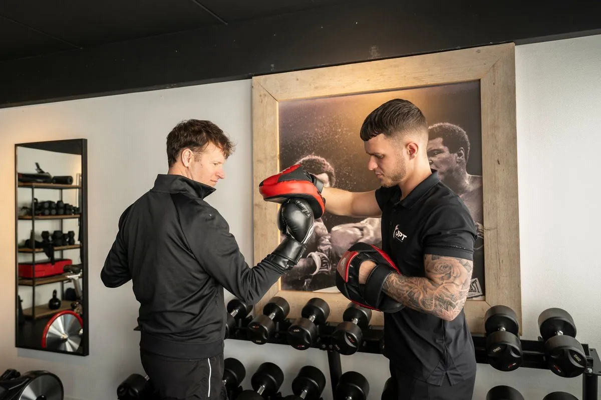 Trainer Aidan geeft bokstraining met pads tijdens een training bij JPT