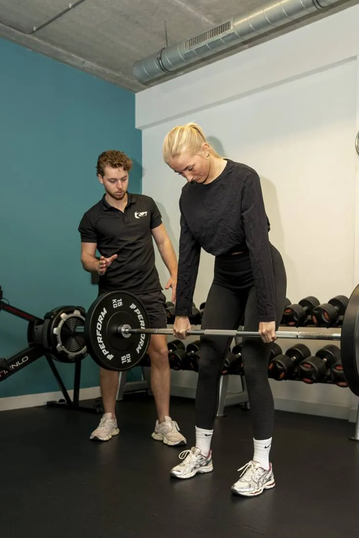 Trainer begeleidt een cliënt bij een deadlift in de trainingsruimte van JPT
