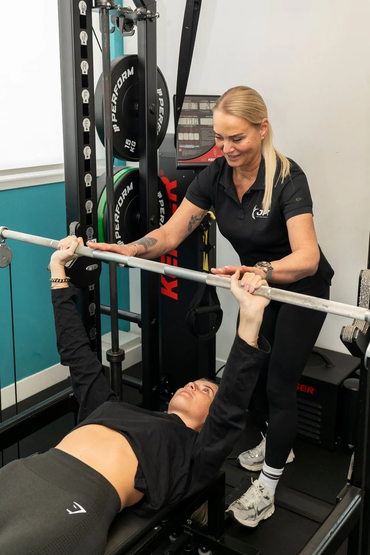 Personal trainer Angelique begeleidt een cliënt bij een krachtoefening in de JPT gym